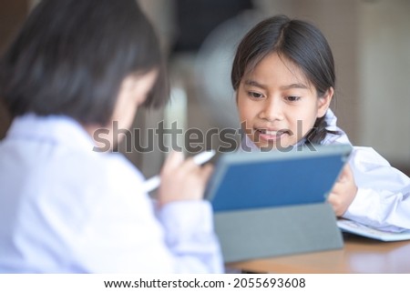Asian children student friends back to school and study together using digital tablet and write on notebook at school afet Covid-19 lockdown. Back to School Concept Stock Photo