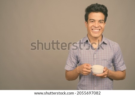 Studio shot of young Asian businessman against gray background