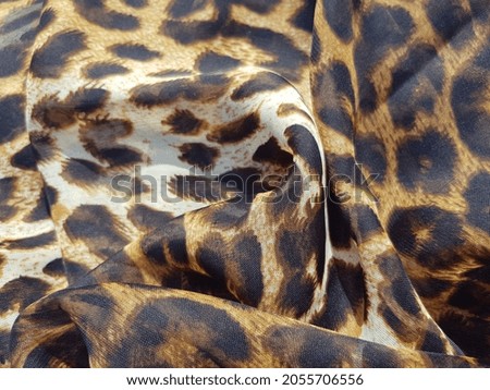 Wavy translucent fabric with leopard print, in folds (texture).