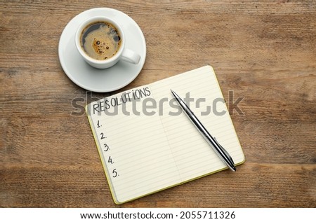 Making new year's resolutions. Notebook with pen near cup of coffee on wooden table, flat lay