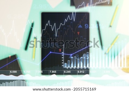 Abstract creative financial graph and modern digital tablet on desktop on background, top view, financial and trading concept. Multiexposure