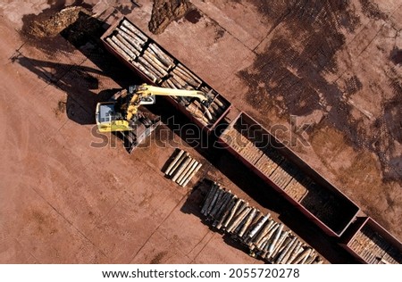 Excavator with log grab crane unloads timber from freight car. Crane with claw loads logs onto log train for lumber mill. Illegal logging and timber export. Wood Machine and Log Grabbing.
 Royalty-Free Stock Photo #2055720278