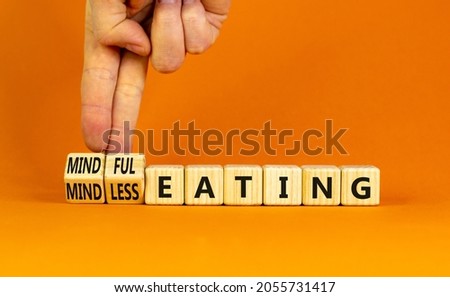 Mindful or mindless eating symbol. Doctor turns cubes and changes words mindless eating to mindful eating. Beautiful orange background, copy space. Medical and mindful or mindless eating concept. Royalty-Free Stock Photo #2055731417