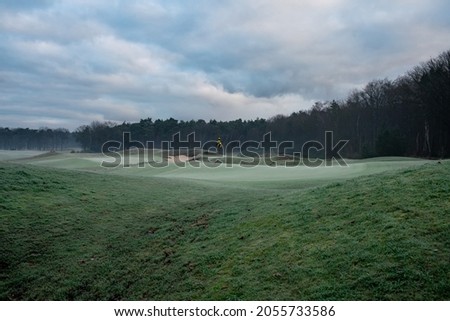 A beautiful winter golf course with early morning frost, calm weather, gray-green colors, soft lines. Royalty-Free Stock Photo #2055733586