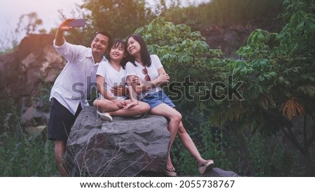 Happy family taking selfie  on the rock mountain with sunset.Concept of technology for lifestyle