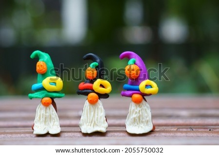 Figures of three dwarfs made of plasticine, decorated with a festive hat and a pumpkin. The concept of Halloween.