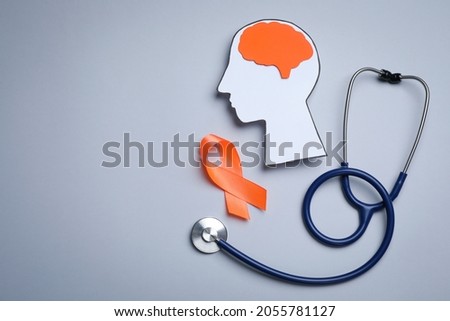 Human head cutout, brain, orange ribbon and stethoscope on grey background, flat lay with space for text. Multiple sclerosis concept Royalty-Free Stock Photo #2055781127