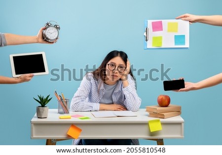 Deadline and multitask concept. Tired asian lady stressed by a lot of work, sitting at the desk over blue background and looking at camera. Hands with tablet, watch, tasks and smartphone Royalty-Free Stock Photo #2055810548