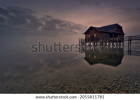 The big boathouse on the Ammersee. In the morning at 6:30 a.m. Royalty-Free Stock Photo #2055811781