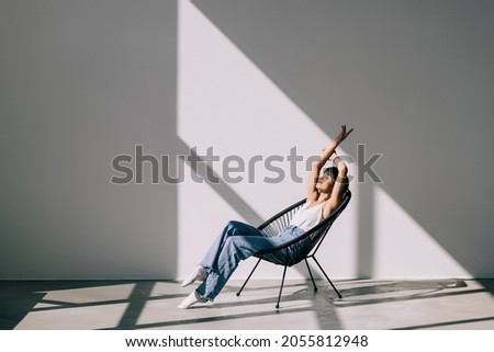 Young woman at home sitting on modern chair relaxing in her living room Royalty-Free Stock Photo #2055812948