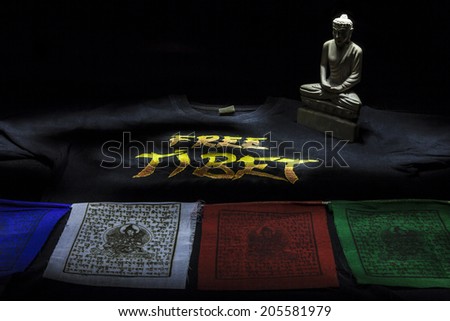 Prayer flags with Free Tibet t-shirt and buddha statue isolated on a black background 