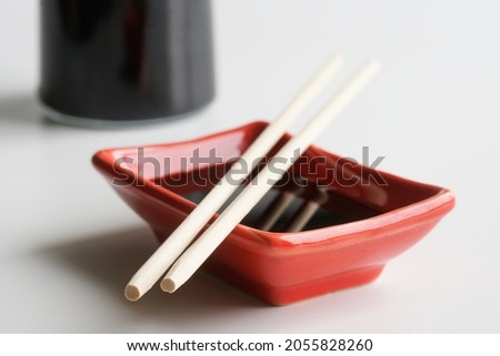Rectangular Japanese sauce bowl - seyuzaru, chopsticks - varibashi and a bottle of soy sauce on a light background. Close-up