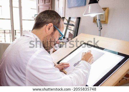 Artist drawing at the work table in his painting studio. Selective focus