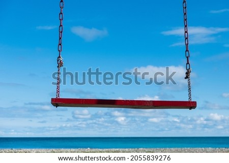 wooden swing on the background of the empty seashore. nobody here. season is over