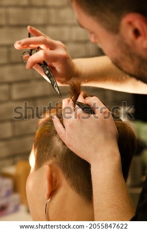 Hairdresser cutting client's hair in beauty salon