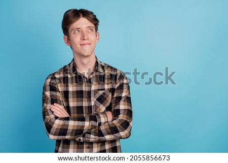 Photo of young attractive man happy dream curious look empty space crossed hands isolated over blue color background