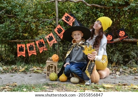 halloween. Young woman with her son having fun with pumpkins on the background of festive characters outdoors. holiday "wallet or life"