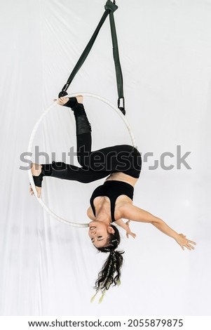 Woman aerial acrobat hanging in aerial hoop or aerial ring practice at studio