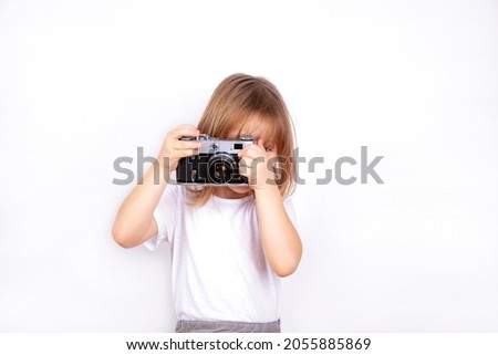 A little girl holds a vintage camera in her hands and takes pictures.