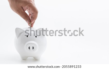 Hand businessman save money into white piggy bank on white background with copy space. Savings money for investment of buy sales home estate, and education for the children to the future.