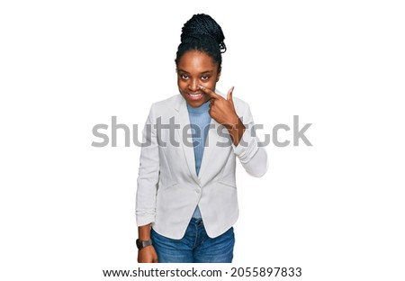Young african american woman wearing business clothes pointing with hand finger to face and nose, smiling cheerful. beauty concept 