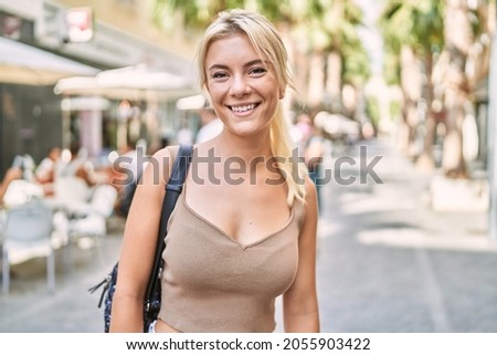Young blonde girl smiling happy standing at the city