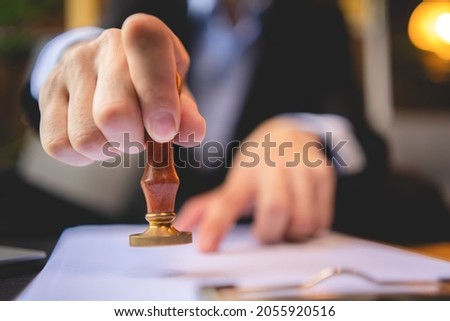Close-up of a person's hand stamping with approved stamp on approval certificate document public paper at desk, notary or business people work from home, isolated for coronavirus COVID-19 protection Royalty-Free Stock Photo #2055920516