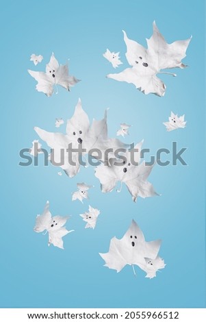 White maple leaves looking like ghosts and falling down against light blue background. Creative Halloween celebration concept. Minimal scary and spooky 31th October party invitation card.