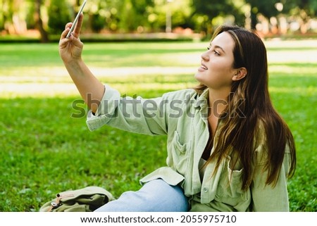 Mobile connection application.Young teenager student freelancer woman taking selfie photo image, having video call conversation meeting on smart phone on social media in park.
