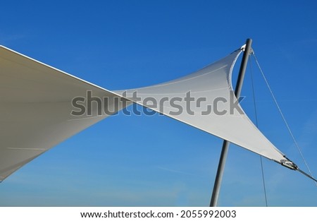 white tarpaulin taut, shading from the sun and rain over the terrace of the restaurant, on the playground in the kindergarten, on the platform. just a mast and taut ropes attached firmly to the ends Royalty-Free Stock Photo #2055992003