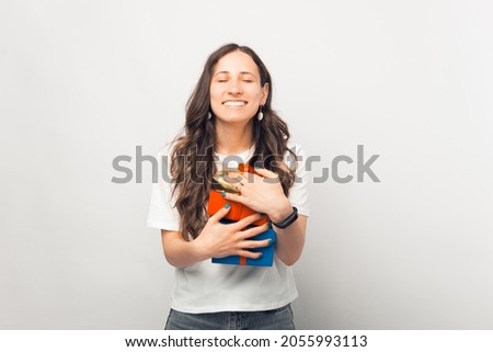 Thankful young lady is holding a bunch of gifts over white background. She has a pleased face.