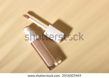 Concealer cream on a background with shadows. Face corrector on beige background with copy space. Blank mockup for product Royalty-Free Stock Photo #2056003469