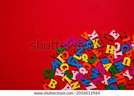 Random colorful alphabet on a red background, colorful letters. Top view.