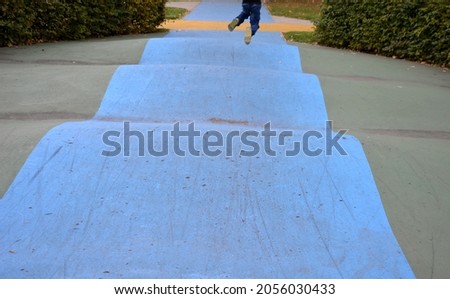 Skateboard, skating park for roller skating with a concrete cement surface painted blue and yellow. turns and training waves with obstacles. Freestyle cycling, children Protective clothing
