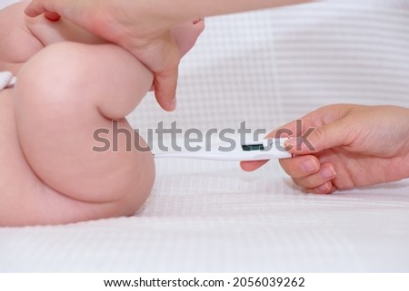 Hand of a woman taking rectal fever of  a baby Royalty-Free Stock Photo #2056039262