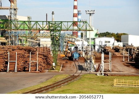 Freight train unloads round timber at a wood processing plant. Excavator with log grab crane unloads timber from freight car. Crane with claw loads logs onto log train for lumber mill. 
 Royalty-Free Stock Photo #2056052771