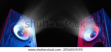 Two sound speakers in neon light with sound wave between them on black. Royalty-Free Stock Photo #2056054595