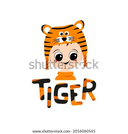 Boy with big eyes and wide smile in tiger hat with lettering. Cute kid with happy face in festive costume for New Year, Christmas and holiday. Head of adorable child with smile emotions