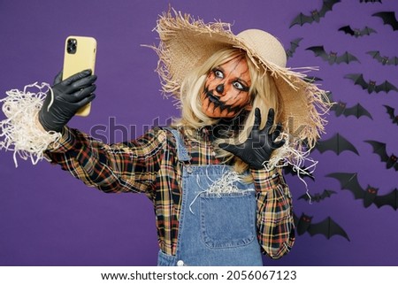 Young woman 20s with Halloween makeup mask in straw hat costume do selfie shot mobile cell phone post photo on network isolated on plain dark purple background studio Celebration holiday party concept