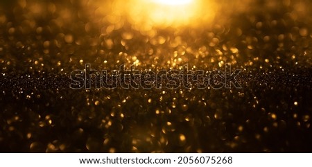 Background of gold and black glitter lights. De-focused abstract background.
