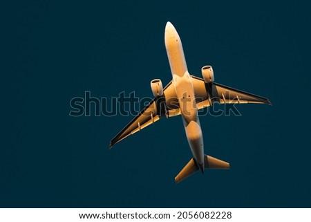 Airliner taking off from Frankfurt airport during golden hour. The sun light lets the airplanes fuselage glow orange. The airplane is isolated on a dark blue background, making it a great wallpaper Royalty-Free Stock Photo #2056082228