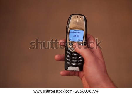 Setting up early alarm on an old mobile phone Royalty-Free Stock Photo #2056098974