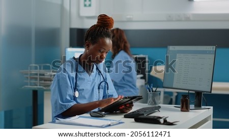 African american nurse holding digital tablet for checkup visit in doctors office. Black woman working as medical assistant, using device with touch screen for healthcare and medicine.