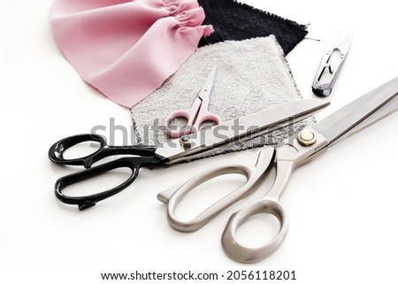 Tailor's scissors are lying on the table, next to scraps of fabric. Concept: atelier, cutting and sewing courses, needlework, custom tailoring, hardware store, self-sewing, website design.
