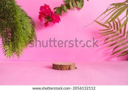 composition ideas concept featuring products. round wood on a pink background decorated with , dry leaves , green leaves and cloth
