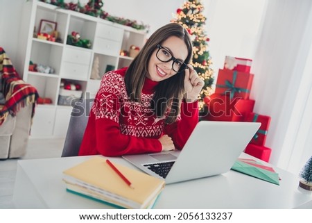 Photo of cheerful businesswoman sit workspace noel eve wear santa hat sweater in decorated x-mas home indoors