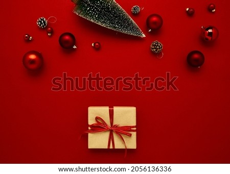 Flat lay composition gift box Christmas baubles on red background for holidays. Top view with copy space