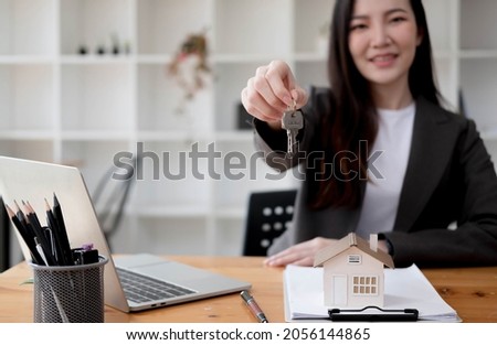 Close up focus on keys, smiling woman realtor selling apartment, offering to client, showing at camera, holding documents, contract, making purchasing deal, real estate agent, mortgage or rent
