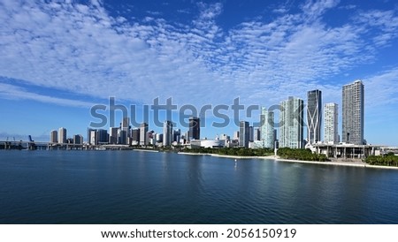 City of Miami, Florida skyline reflected in Biscayne Bay under sunny summer cloudscape.