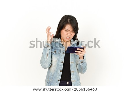 Playing Game on Phone With Angry Face of Beautiful Asian Woman Wearing Jeans Jacket and black shirt Isolated On White Background
